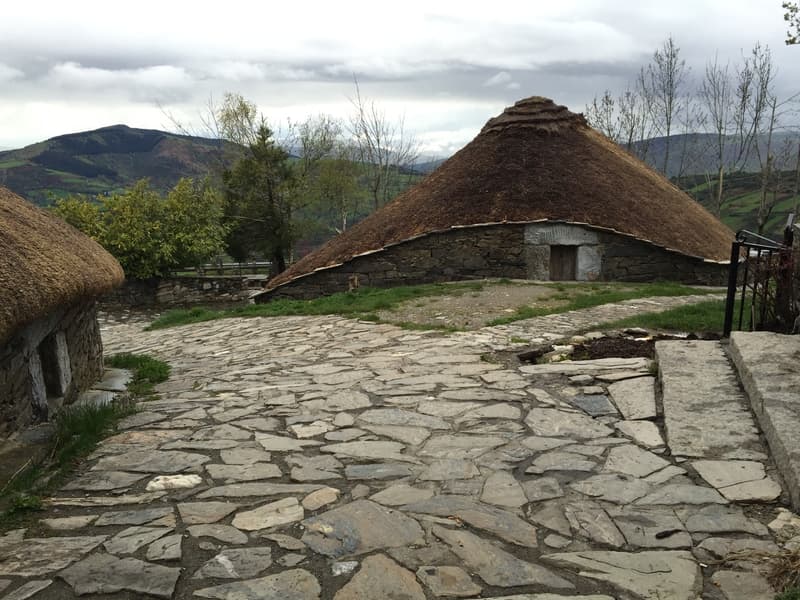 Foto mostra as casas circulares de pedra com telhado de palha, muito comuns no Cebreiro.